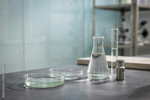 Laboratory glassware with liquid samples and petri dishes on a table