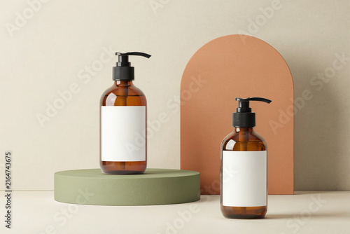 Amber glass pump bottles on podiums with blank white labels for cosmetics
