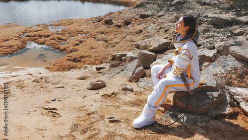 Konstfotografi Homesick astronaut on the rocky shore of a lifeless planet with copy space