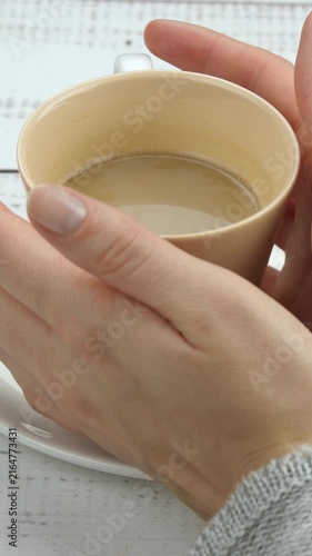 Warm cup of coffee held in hands. Cozy atmosphere invites relaxation and comfort. Enjoyment of hot beverage creates peaceful moment. Vertical composition enhances visual appeal.