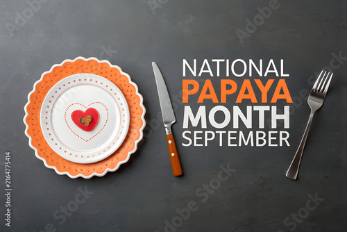 National papaya month september typography inscription with plate and cutlery on dark table