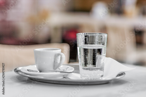 Cup of espresso with a glass of water on a tray in a cafe