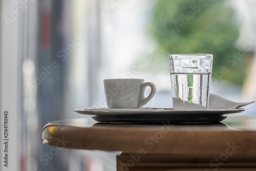 Cup of espresso with a glass of water on a tray in a cafe
