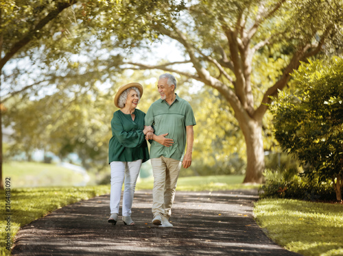 senior couple walking in park smiling
