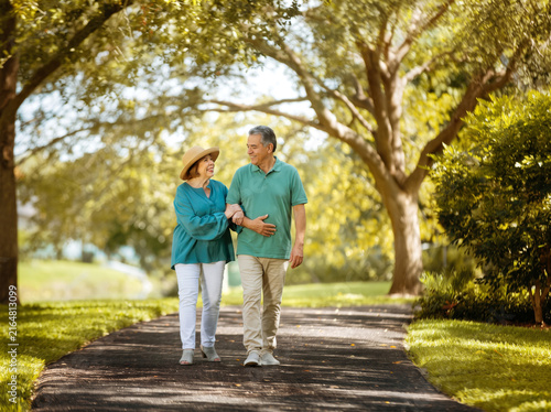 senior couple walking in the park smiling