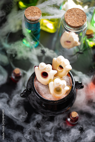 Foto Spooky Halloween cauldron filled with ghost shaped candy and surrounded by potio