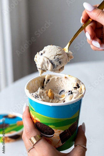 Woman holding ice cream scoop with cookie dough flavor in container  