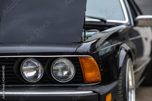 Front view of vintage black classic car with round headlights and open hood