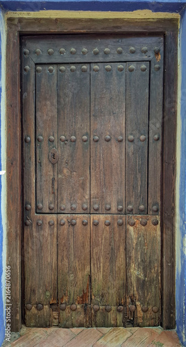 Obraz na płótnie Rustic wooden door with metal studs and a vintage keyhole in an old building