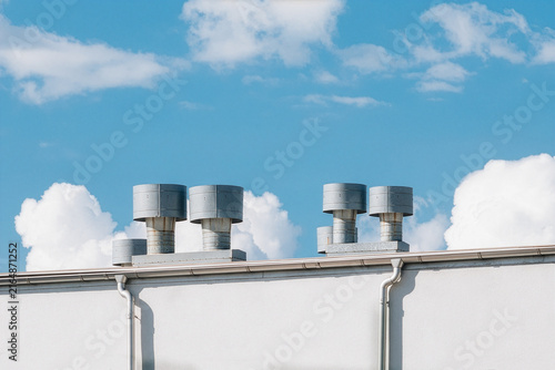 Metal Rooftop Ventilation Vents on White Building Under Blue Sky