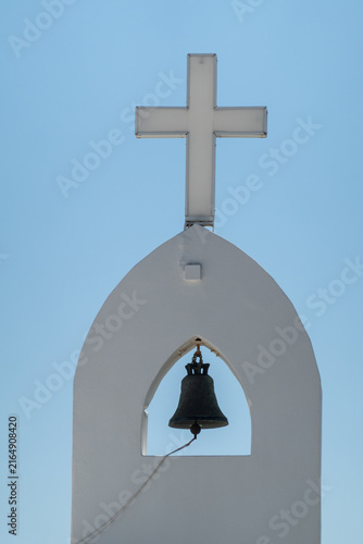 Creek orthodox church bell and cross against blue sky