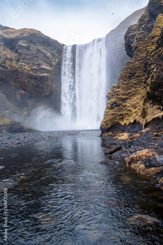 Vertical photography of the majestic Skogafoss waterfall in southern Iceland on a cloudy day in March