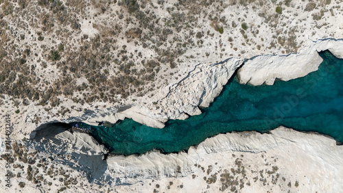 Aerial view of white coastal rocks surrounded by deep blue water near Mandrakia, Milos, Greece, showing the island’s striking geology.