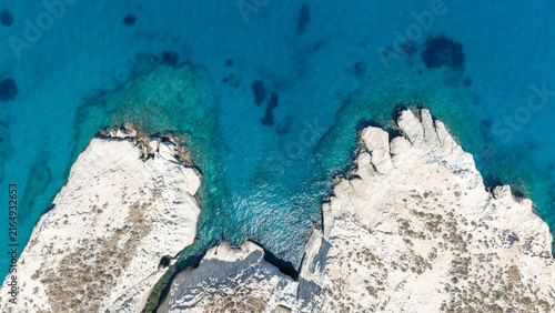 Aerial view of white coastal rocks surrounded by deep blue water near Mandrakia, Milos, Greece, showing the island’s striking geology.
