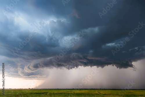 Obraz na płótnie Low shelf cloud rolling across the sky with a wall of rain sweeping over a brigh