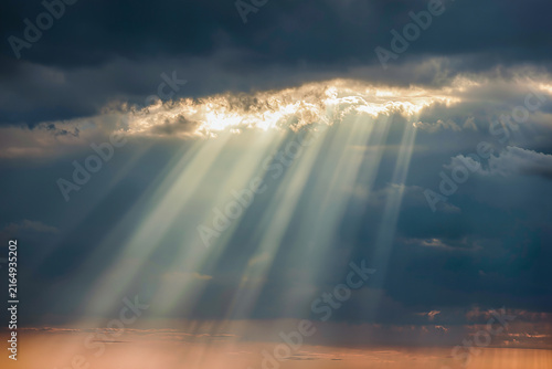Foto Golden crepuscular rays bursting through a break in dark storm clouds and stream