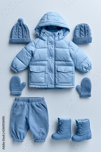 Toddler winter clothing set on light gray background with padded jacket, hat, mittens, trousers, and boots arranged together Generative AI