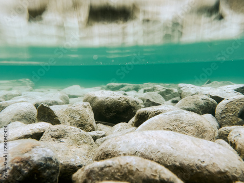 Rocks in the lake in shallow water with rocks reflecting on top of the water