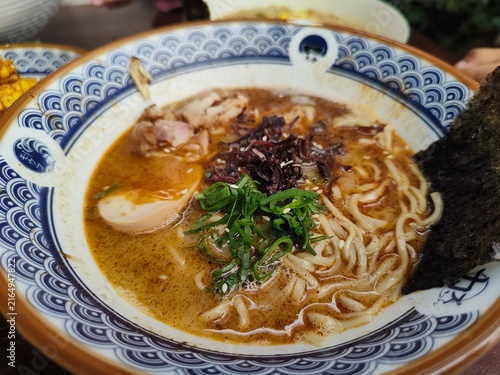 Close up of a delicious bowl of Japanese ramen noodles with rich broth, sliced meat, soft-boiled egg, scallions, and nori, authentic Asian culinary concept.