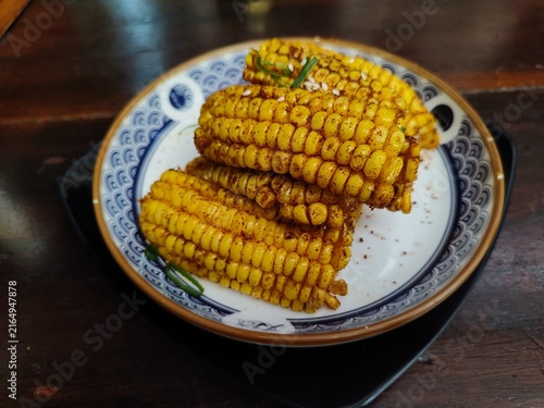 Crispy fried corn tossed with spicy chili powder served on an aesthetic ceramic plate, delicious savory snack and Mexican street food concept.
