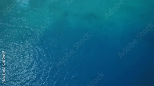 An aerial view of calm blue ocean water with gentle ripples sparkling under sunlight.