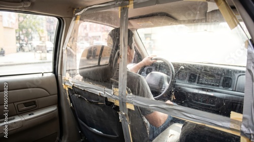 Driver operating taxi with makeshift plastic protective barrier