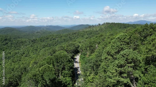 A single car traveling up a road winding through Oconee State Park with the foothills in the background in northwest South Carolina.