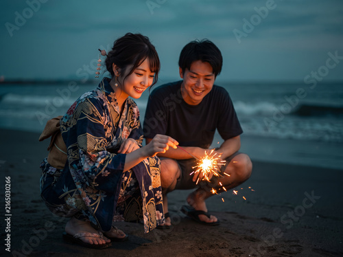 海辺で線香花火を見つめ合う男女
