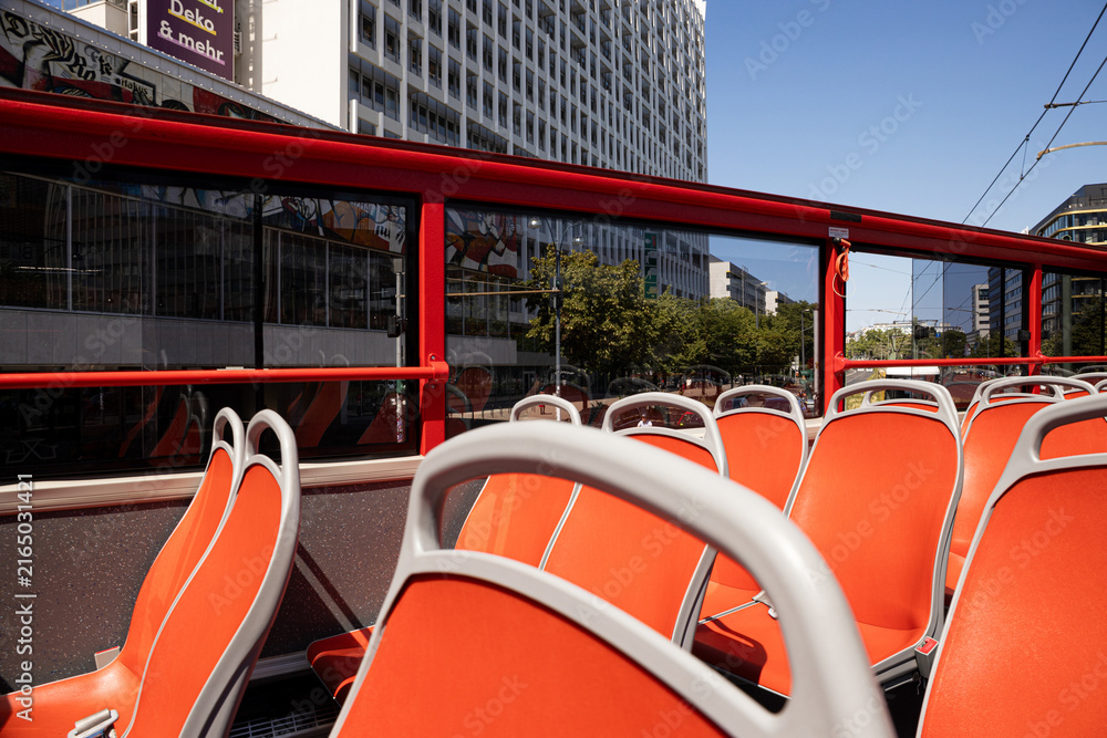 Fototapeta premium Open-top bus offers empty seats with city buildings in backdrop