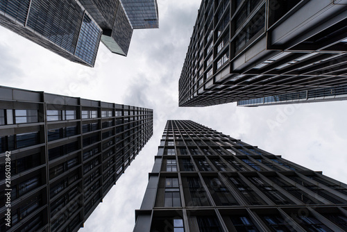 Towering residential buildings converging around a cloudy sky