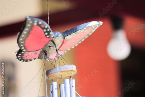 Obraz na plátně A hanging decoration featuring a butterfly shape with a bell underneath; it produces a soothing, melodious tinkling sound when caught by the breeze