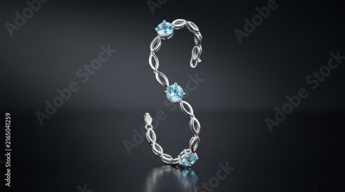 Elegant silver letter S shaped jewelry piece with blue gemstones.