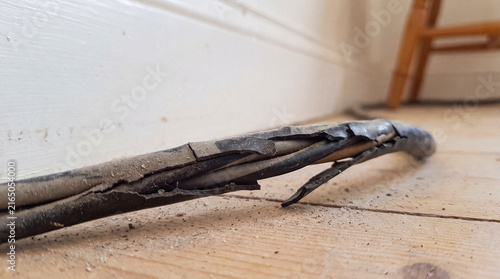 A dangerously frayed electrical cable with visible internal wires and dust.