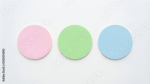 Three colorful round badges or stickers in pink, green, and blue colors