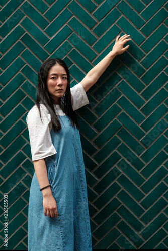 Canvas Print Young asian woman posing by teal herringbone wall
