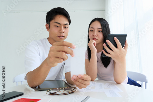 Bild auf Leinwand Young Japanese Man and Woman Discussing Household Finances at Table