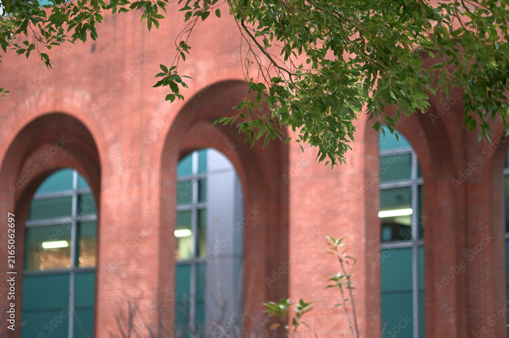 Fototapeta premium New Taipei City, Taiwan - Jan 05, 2025: Red brick arches line a corridor at the National Taiwan Library, glass facade beyond, No. 4 Park, Zhonghe District.