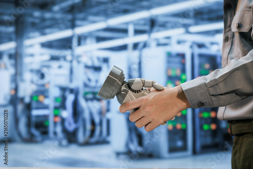 Obraz na płótnie Close view of a factory worker holding a robotic gripper in a modern automated production plant, with blurred industrial machines and control panels behind