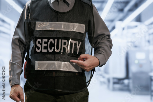 Konstfotografi Close-up of a security guard in uniform wearing a protective vest and pointing at a security badge in a modern indoor building