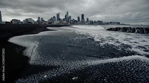 Stormy Black Sand Beach with Distant City Skyline.