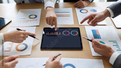Corporate executives collaborating together around wooden conference table viewing interactive analytics dashboard during financial strategy review session indoors. professional stock image 