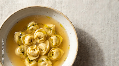 Classic Italian Tortellini in Broth Soup Served in Ceramic Bowl with Olive Oil and Herbs