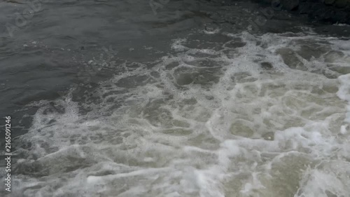 Close-up shot of powerful churning white water and thick foam in a fast-flowing river current. Dynamic nature background showing raw energy and fluid motion.