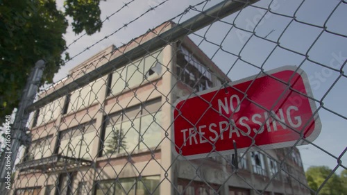 Wide-angle tilting shot of a no trespassing sign on a fence at an industrial location