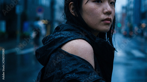 Moody Cinematic Portrait of Young Asian Woman with Raindrops on Face in City Rain