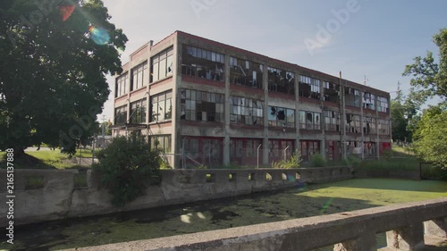 Panning wide shot. Abandoned warehouse with shattered windows. Forgotten, crumbling industrial facility