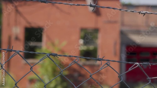 Close-up of barbed wire outside of an abandoned warehouse facility. Old factory. Industrial facility. 