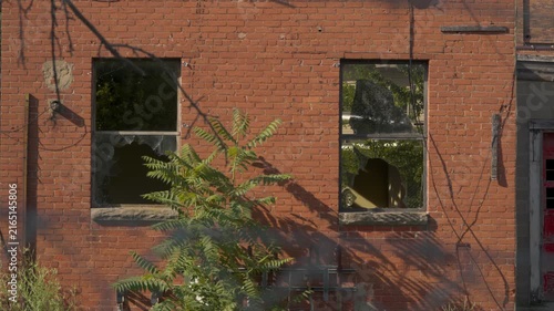 Close-up of two shattered windows on the side of an abandoned factory building. Forgotten industrial facility.