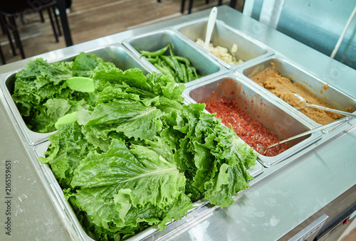 Fotografía Hand holding a fresh green lettuce wrap with grilled meat and spicy paste