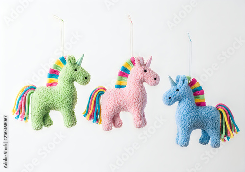 Three colorful plush unicorn toys standing in a row